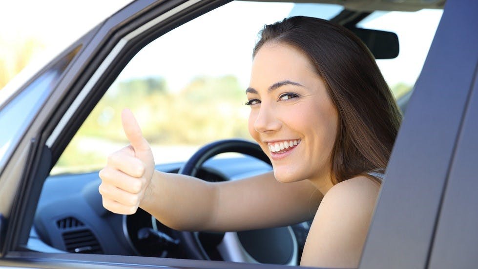 Jeune conductrice souriante au volant de sa voiture