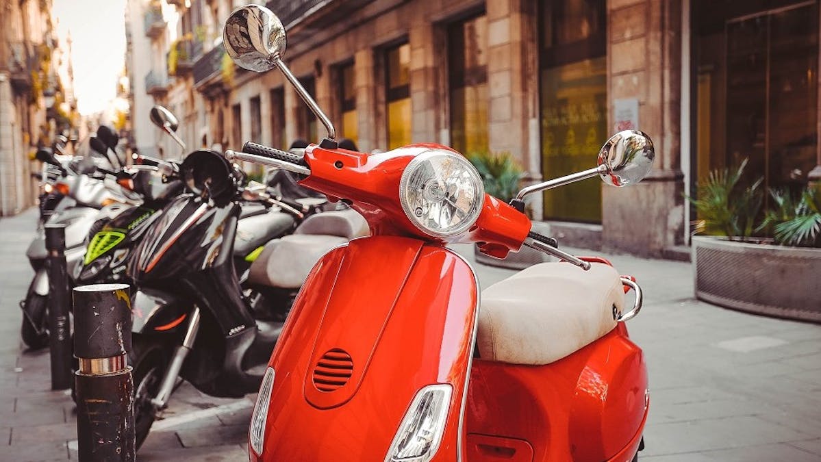 Differents scooters stationnes dans une rue pavee