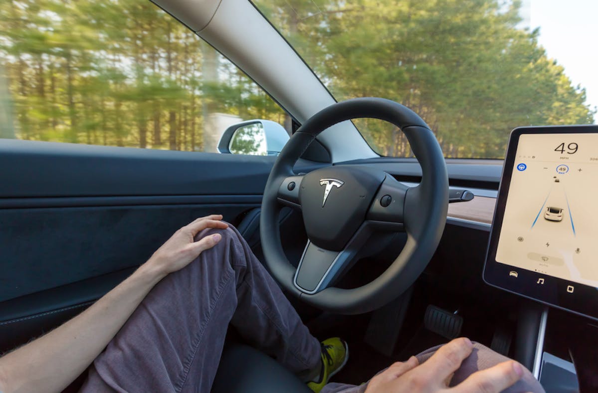 Conducteur au volant d'une tesla en conduite autonome