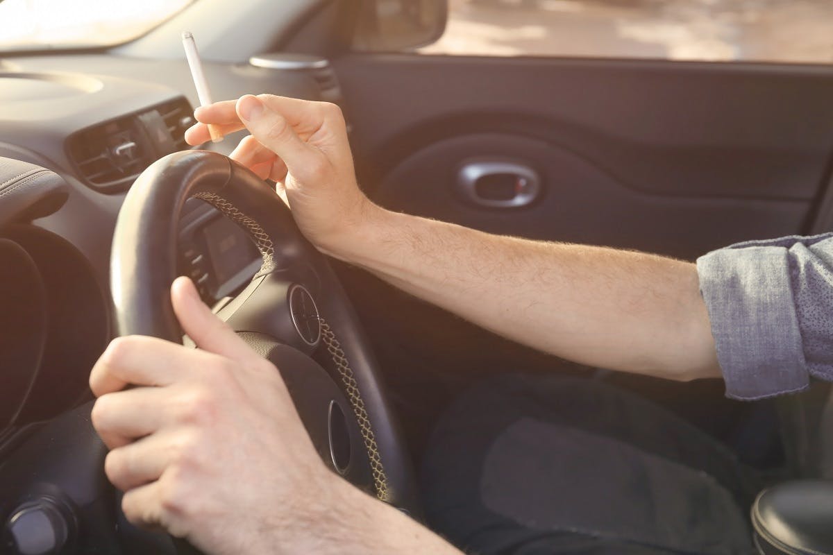 Automobiliste fumant une cigarette au volant