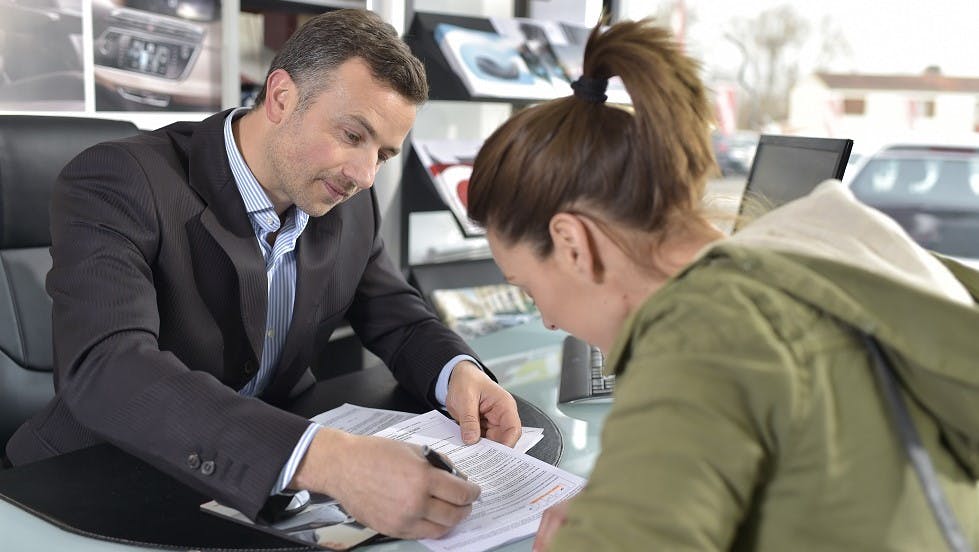 Jeune femme signant un contrat d'assurance auto