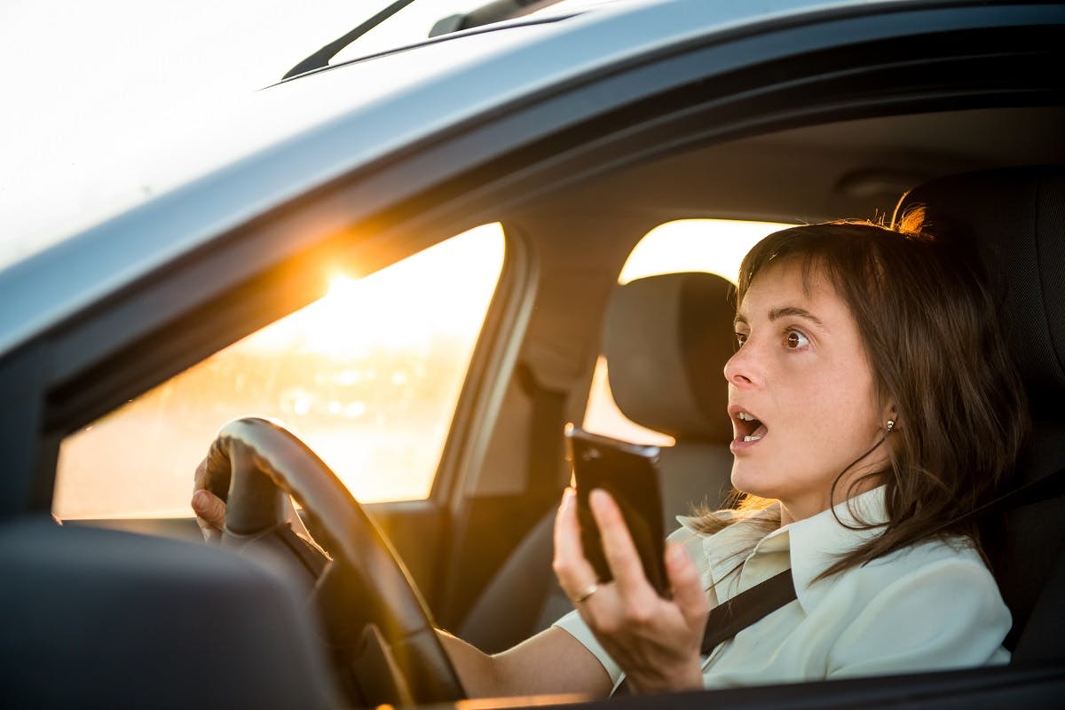 Conductrice roulant avec son telephone en main