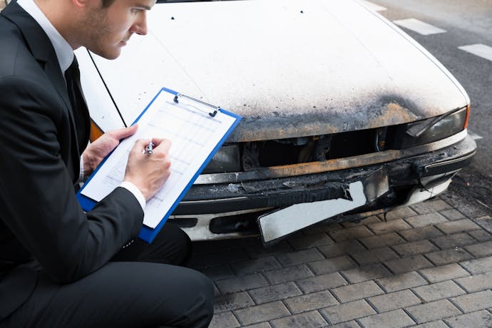 Expert automobile inspectant une voiture incendiee