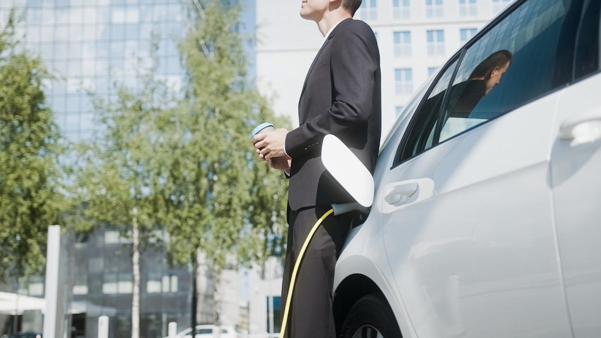 Hommes d'affaires a cote de sa voiture electrique en charge