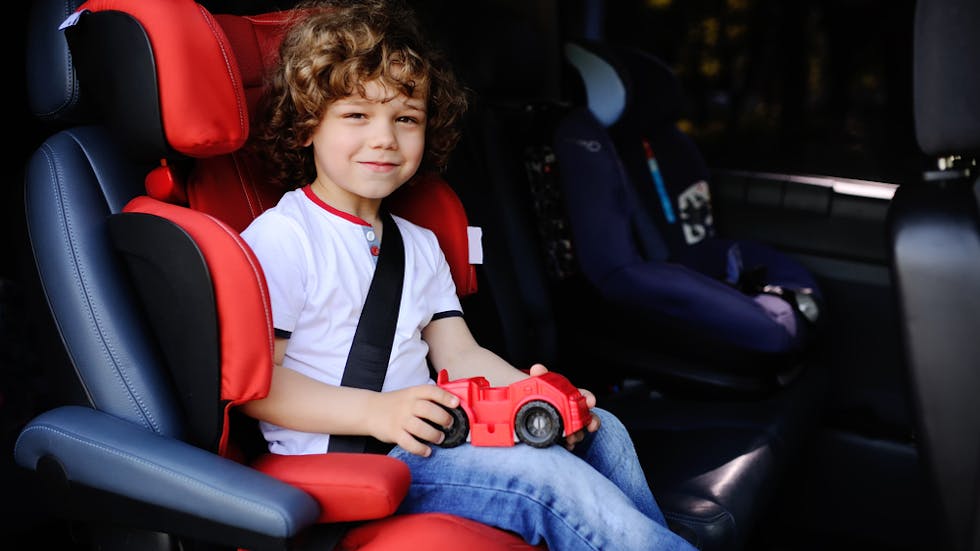Enfant dans un siège auto rouge avec un jouet à la main
