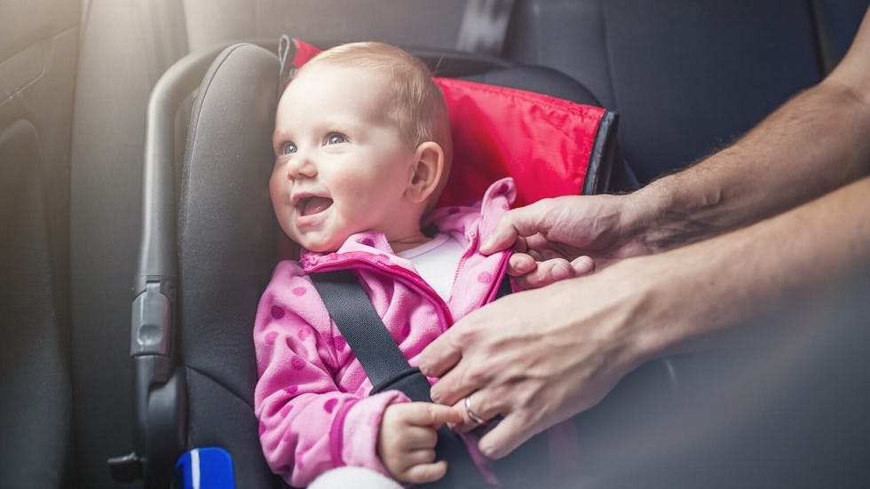 Bebe souriant attache dans son siege auto adapte