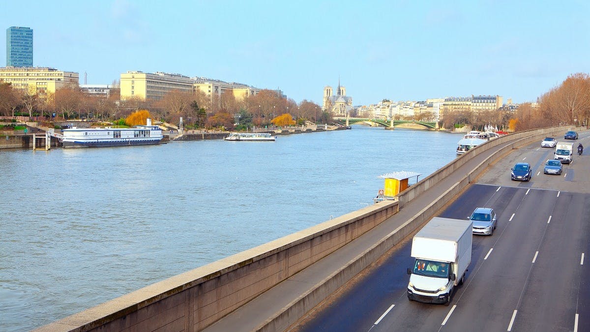 Vehicules circulant a proximite de la Seine avec vue de la cathedrale de Paris