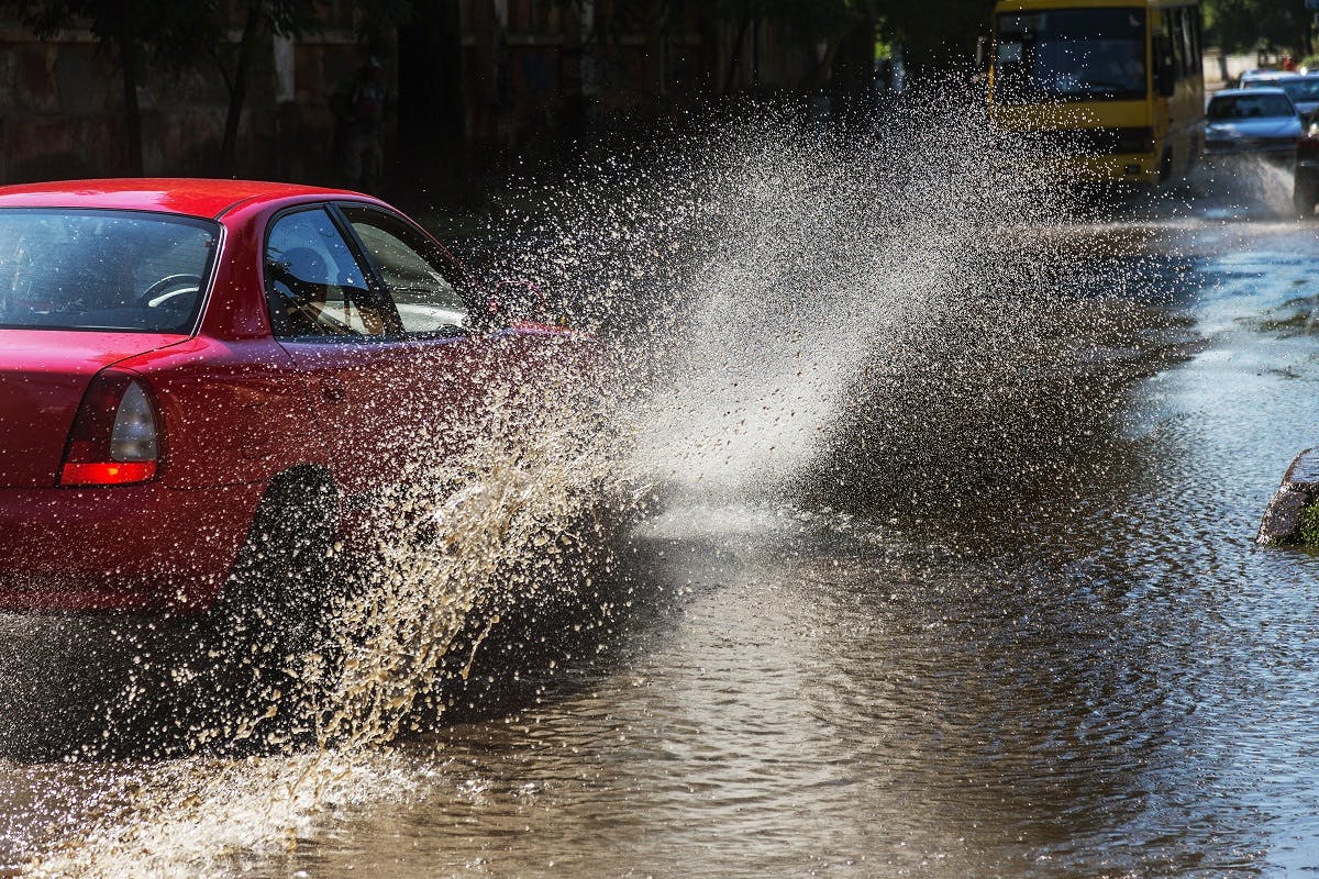 Voiture projetant de l'eau de pluie sur les passants