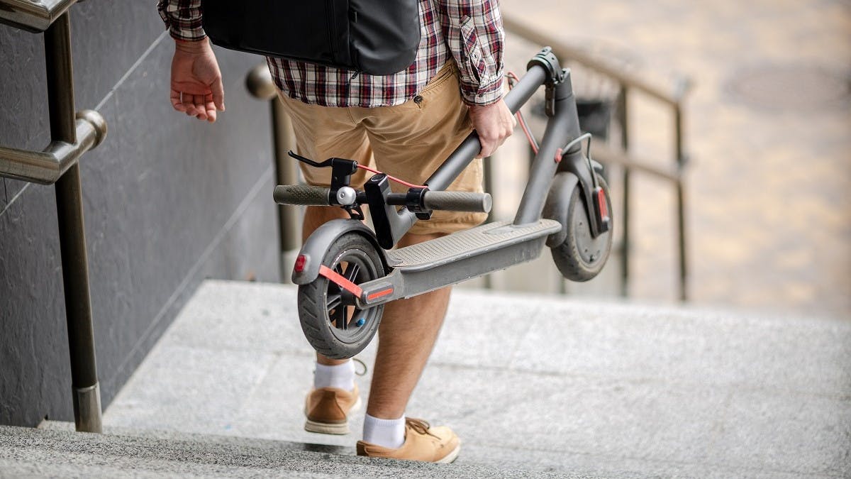 Usager tenant sa trottinette electrique a la main