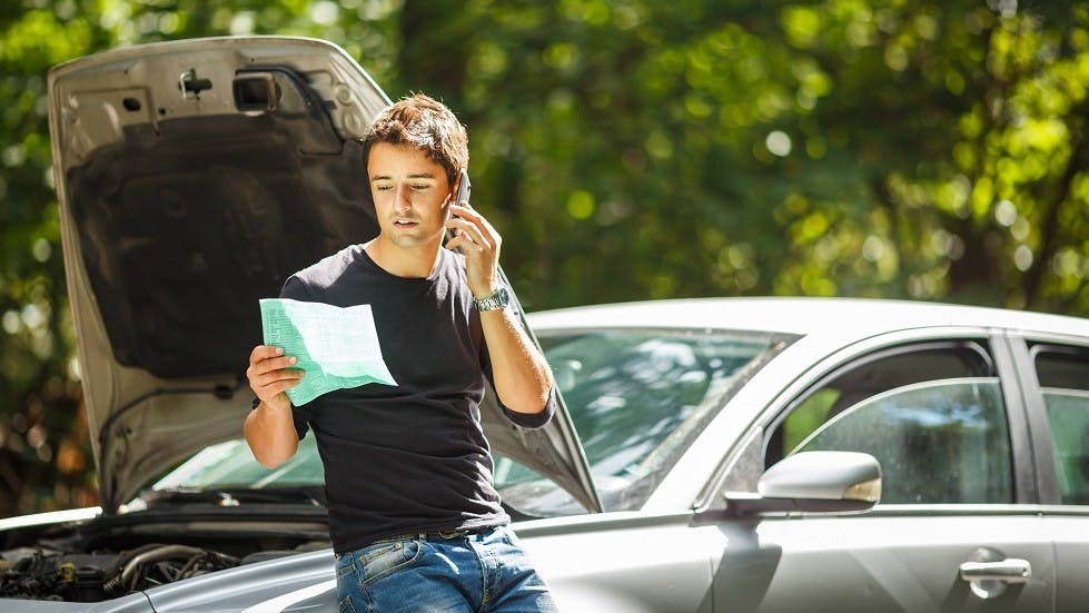 Jeune conducteur en panne appelant son assureur