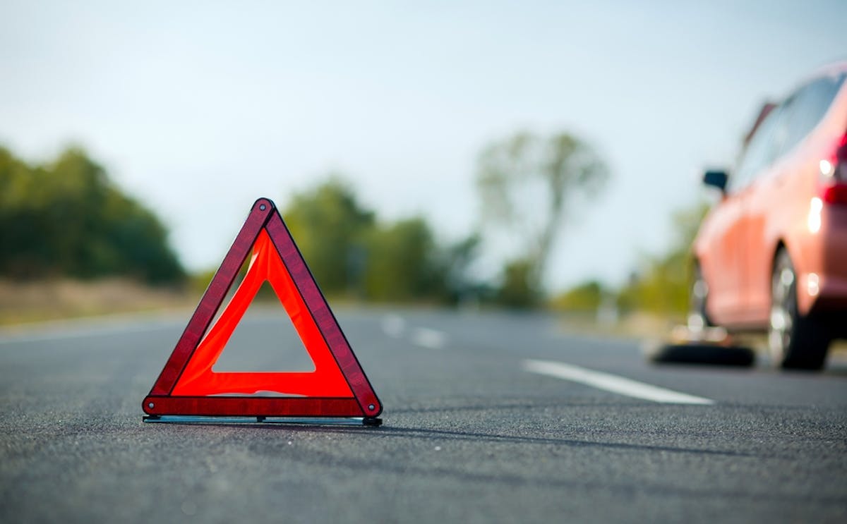 Triangle de signalisation posé sur la route suite à une crevaison