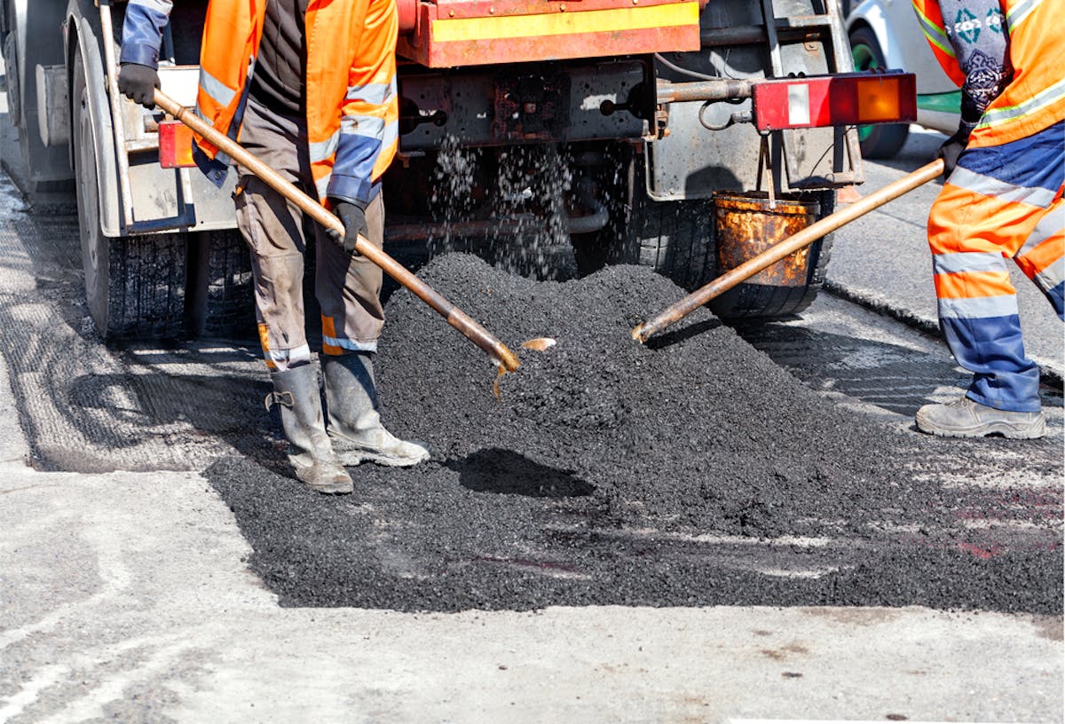 Ouvriers travaillant sur la route en mettant du goudron