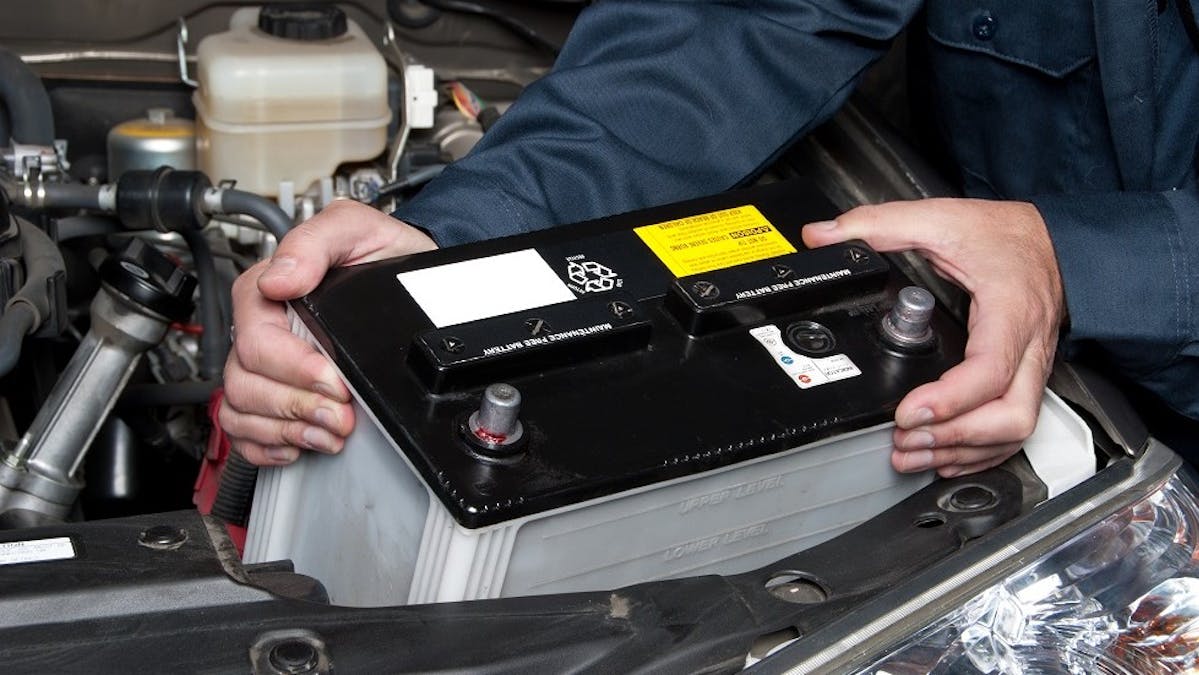 Mecanicien retirant la batterie d'une automobile