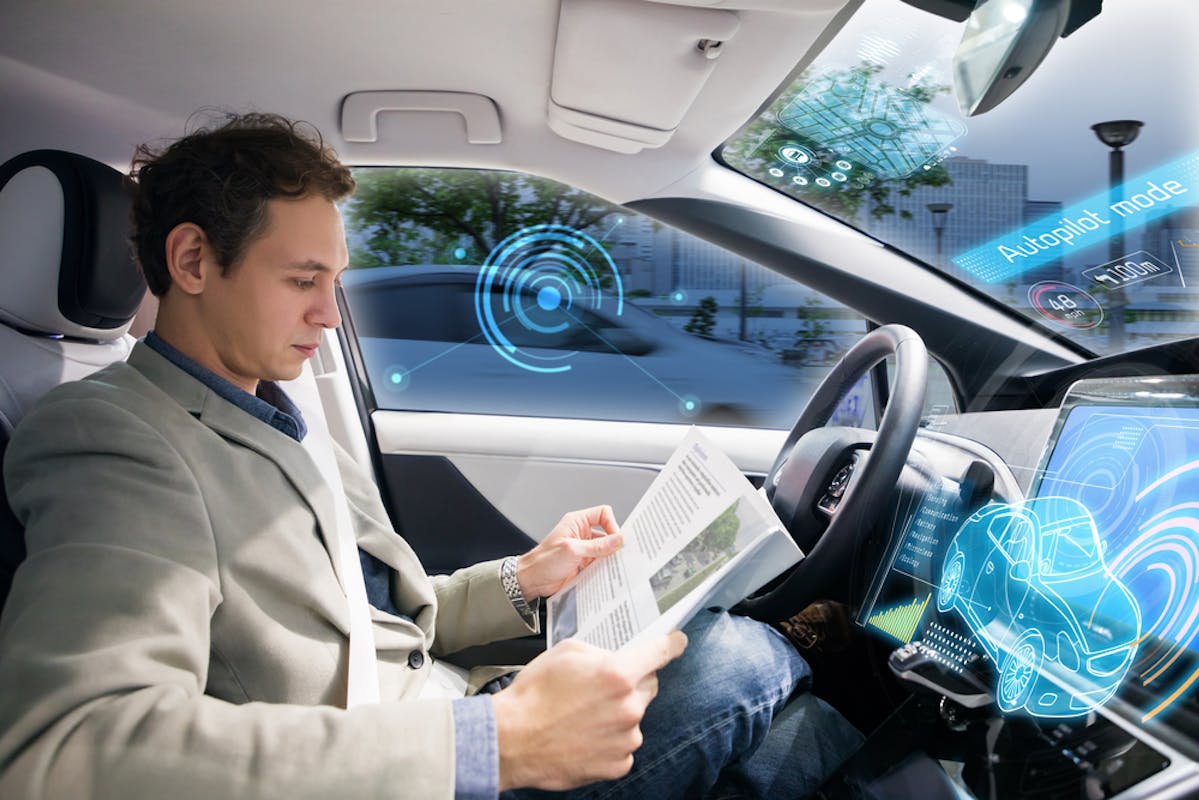 Homme en train de lire un magazine dans sa voiture autonome
