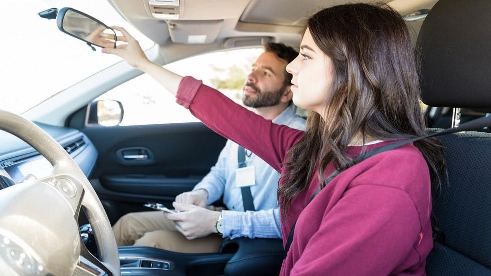 Candidate se formant pour l'examen du permis de conduire reglant son retroviseur