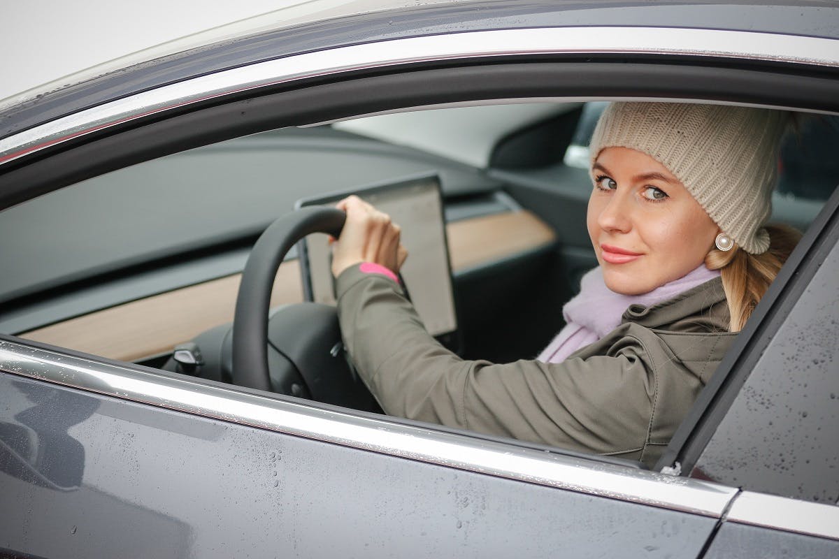 Conductrice de Tesla circulant avec sa vitre ouverte