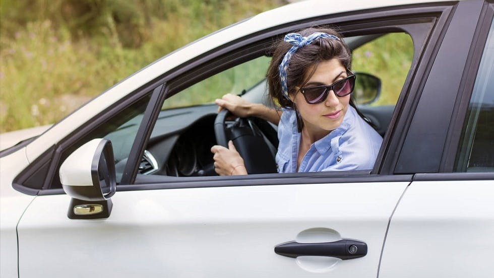 Jeune conductrice garant son automobile en marche arriere