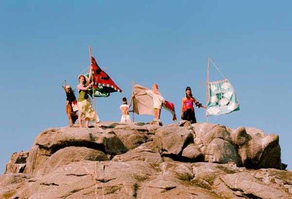 Five models stand on a rocky mound, holding the flags which are the 'banners' of Pangea.  | © Pangea 2023