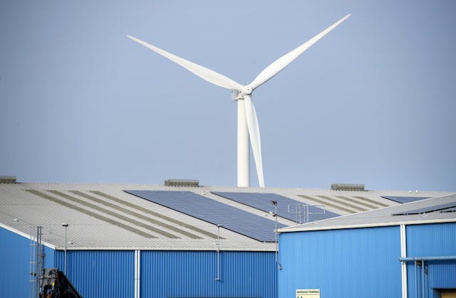 Picture of solar panels on roof and windmill in the background 