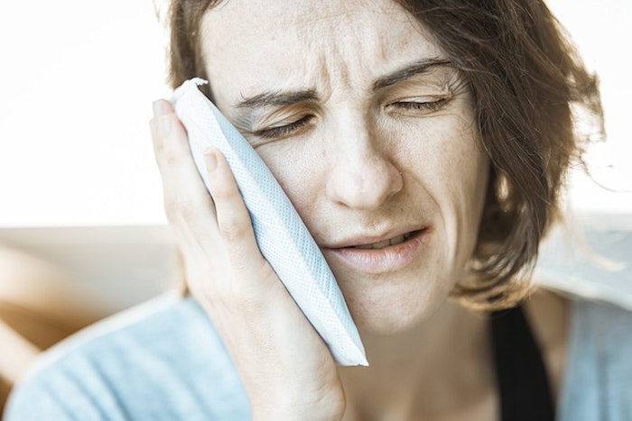 Femme grimaçant de douleur et se tenant la joue