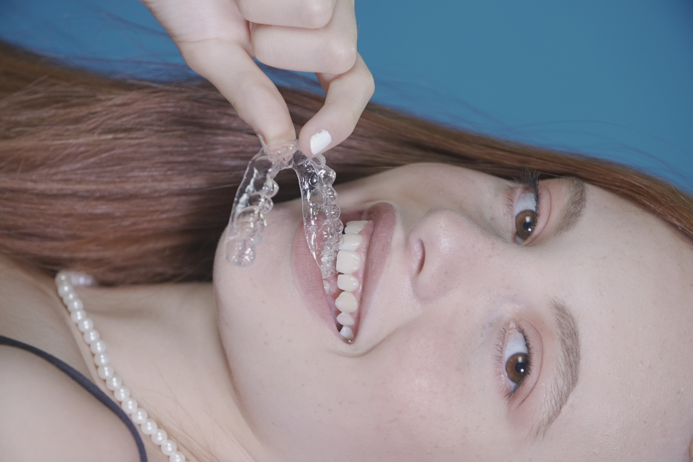 Patiente souriante mettant son aligneur dentaire invisible en bouche