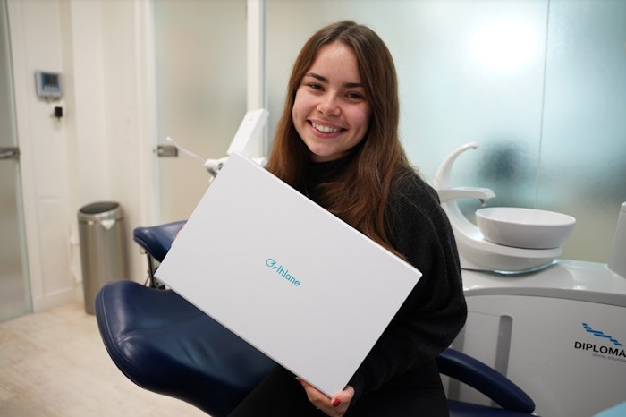 Patiente souriante tenant en main sa box Orthlane contenant son traitement