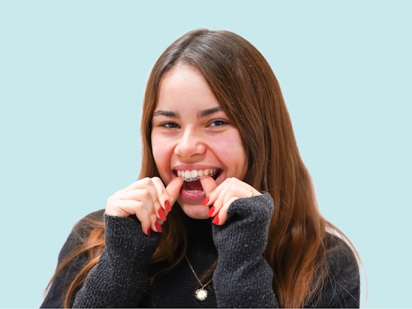 Femme souriant et plaçant son aligneur dentaire