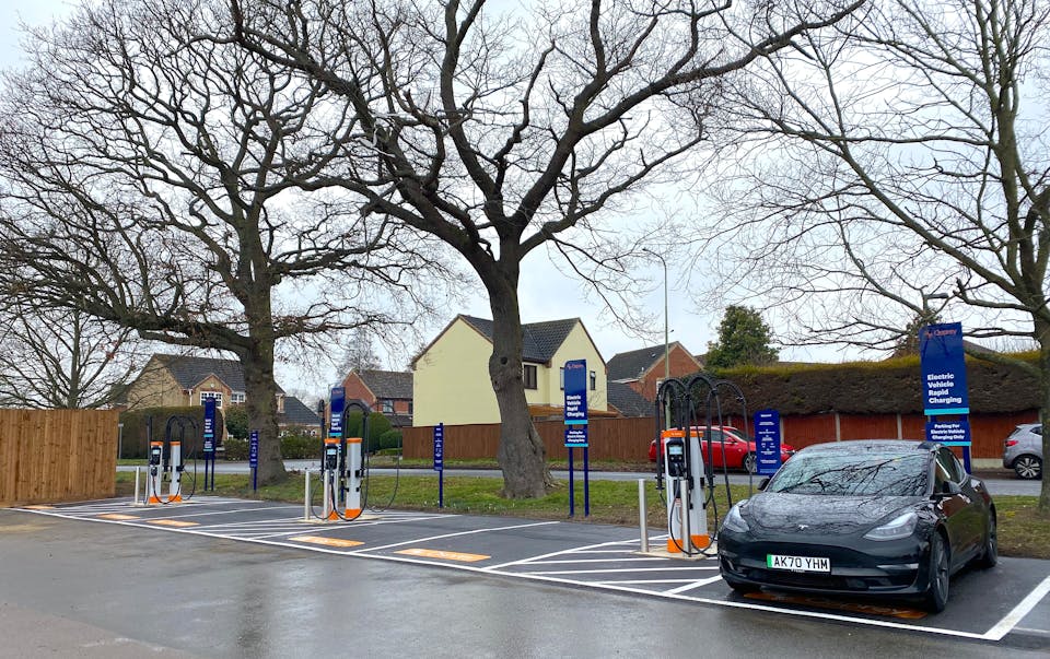 Six high-powered chargers at an Osprey rapid charging hub. A black Tesla is plugged in charging. 