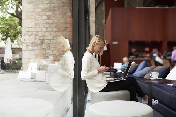 A woman working on her laptop and phone at a cafe table