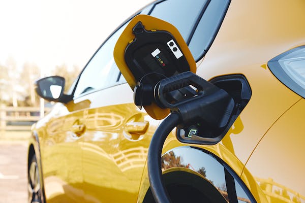 A CCS charging cable plugged in to a yellow electric vehicle