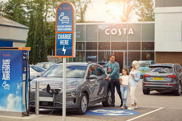 Tonbridge family returning to their charged car with Costa refreshments.