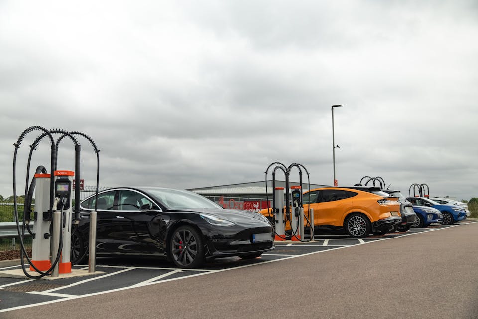 Six electric cars charging at a rapid EV charging hub with eight charge points