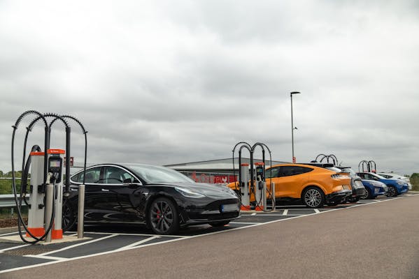 Six electric cars charging at a rapid EV charging hub with eight charge points