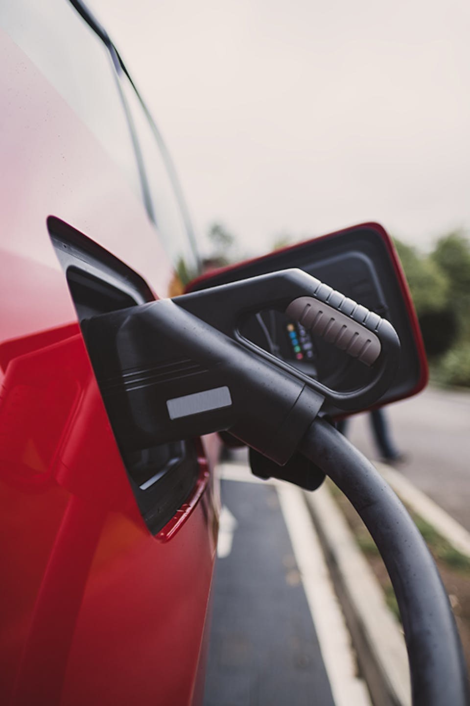 A CCS charging cable plugged in to a red electric car