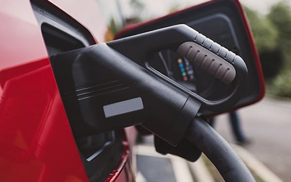 A CCS charging cable plugged in to a red electric car