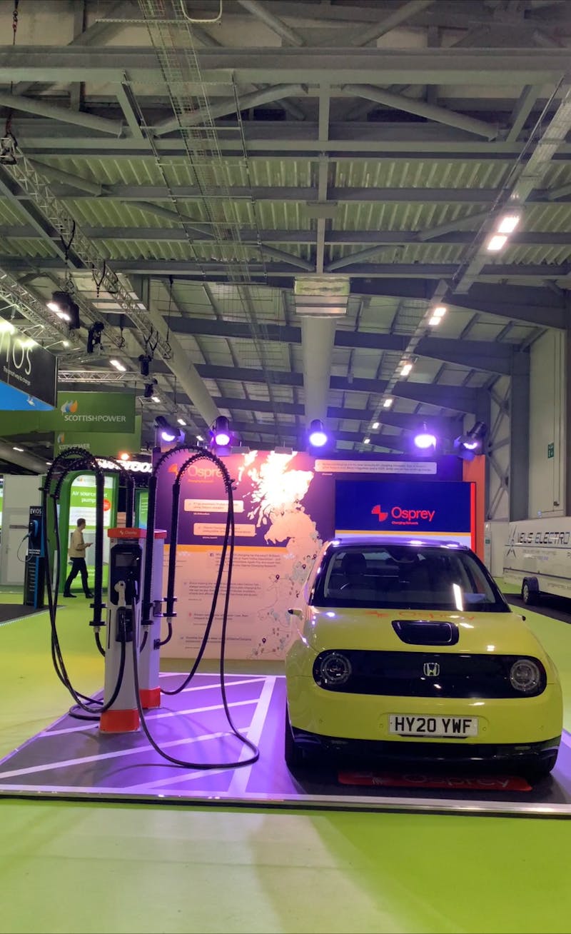 An exhibition stand with two chargers, cross-hatching and a honda-e electric car