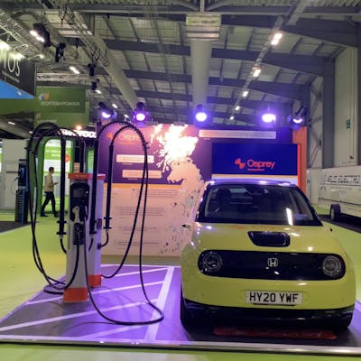 An exhibition stand with two chargers, cross-hatching and a honda-e electric car