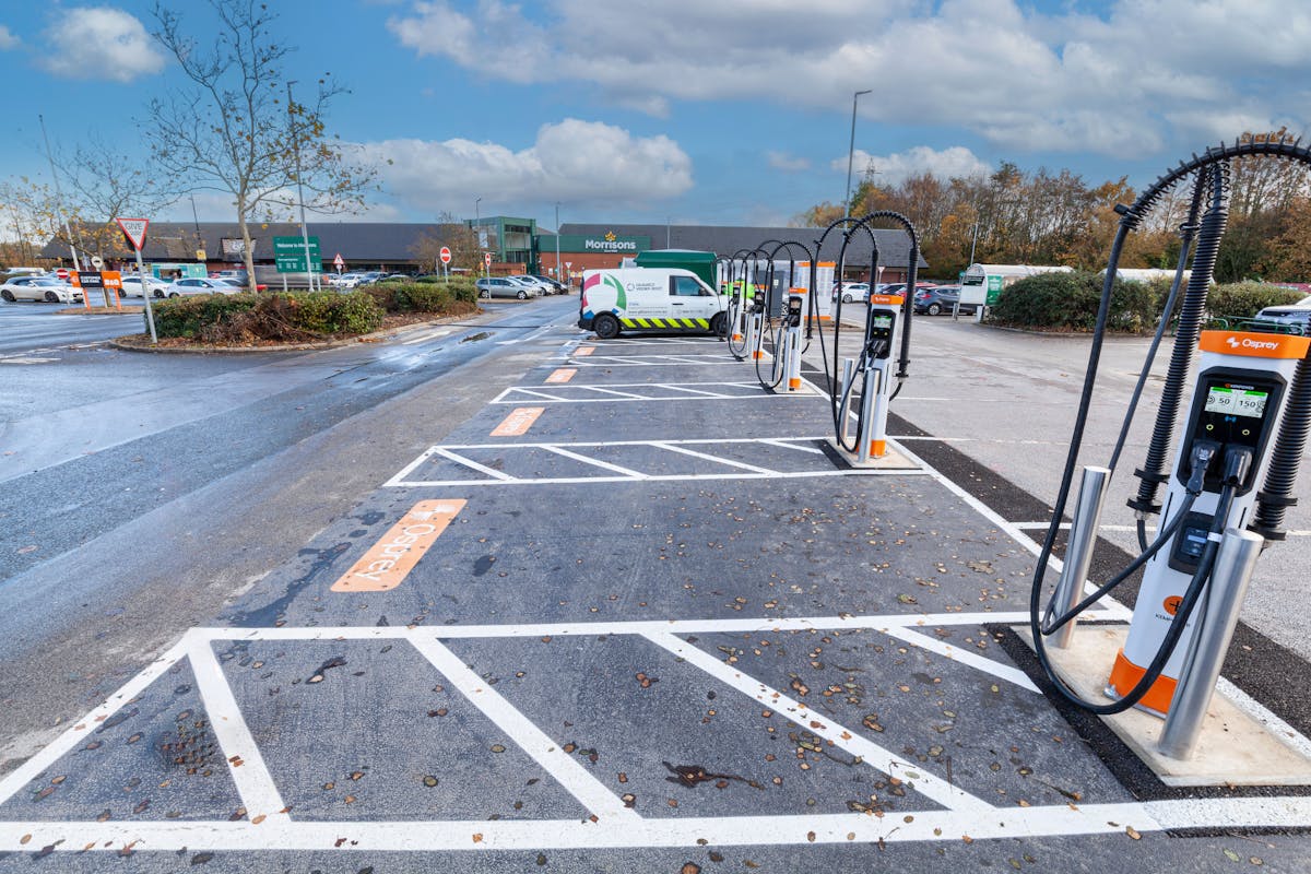 A van parked and charging at an Osprey rapid EV charging hub in front of a Morrisons