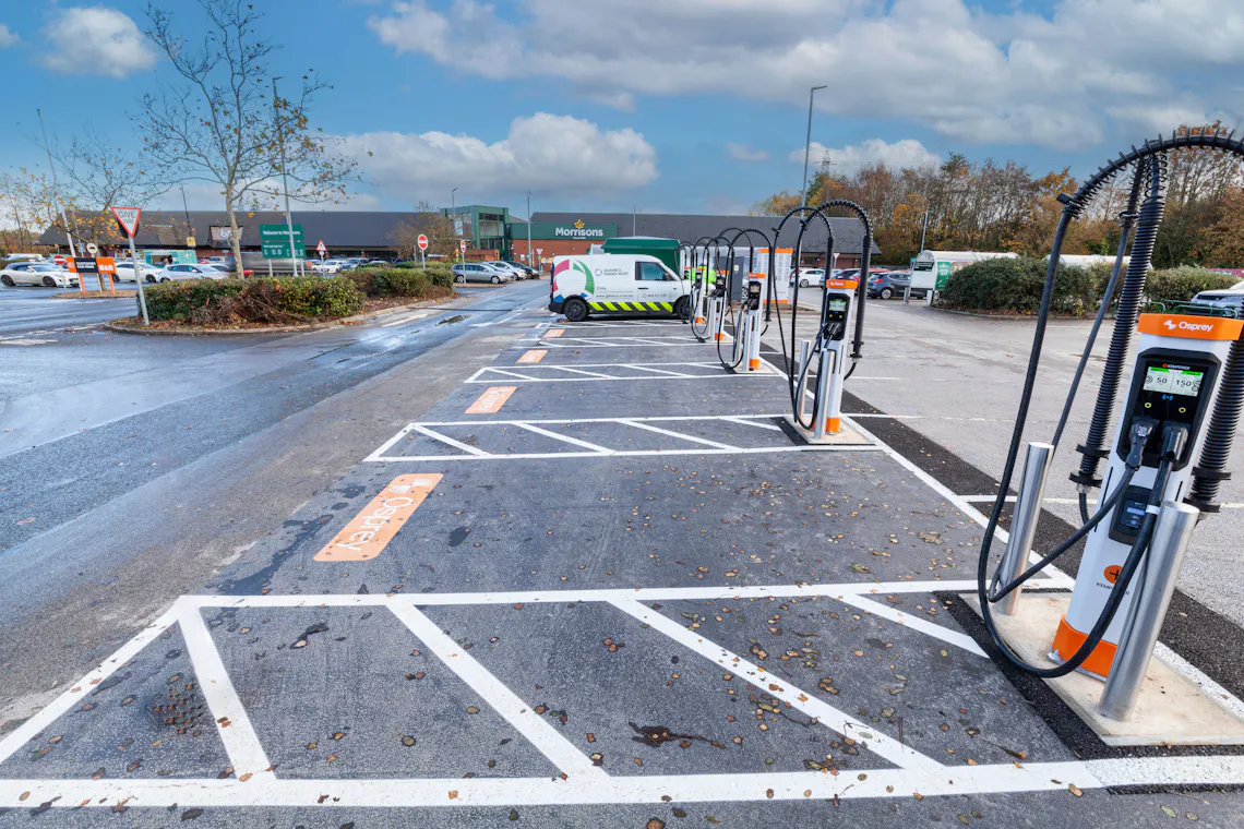 A van parked and charging at an Osprey rapid EV charging hub in front of a Morrisons
