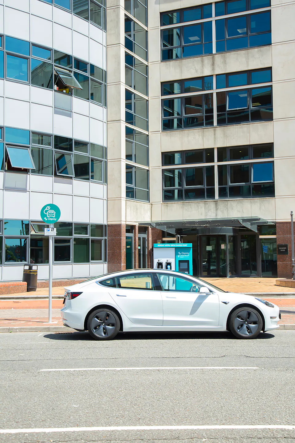 A white Tesla plugged into a Cardiff Council branded 50kW Osprey car charging station
