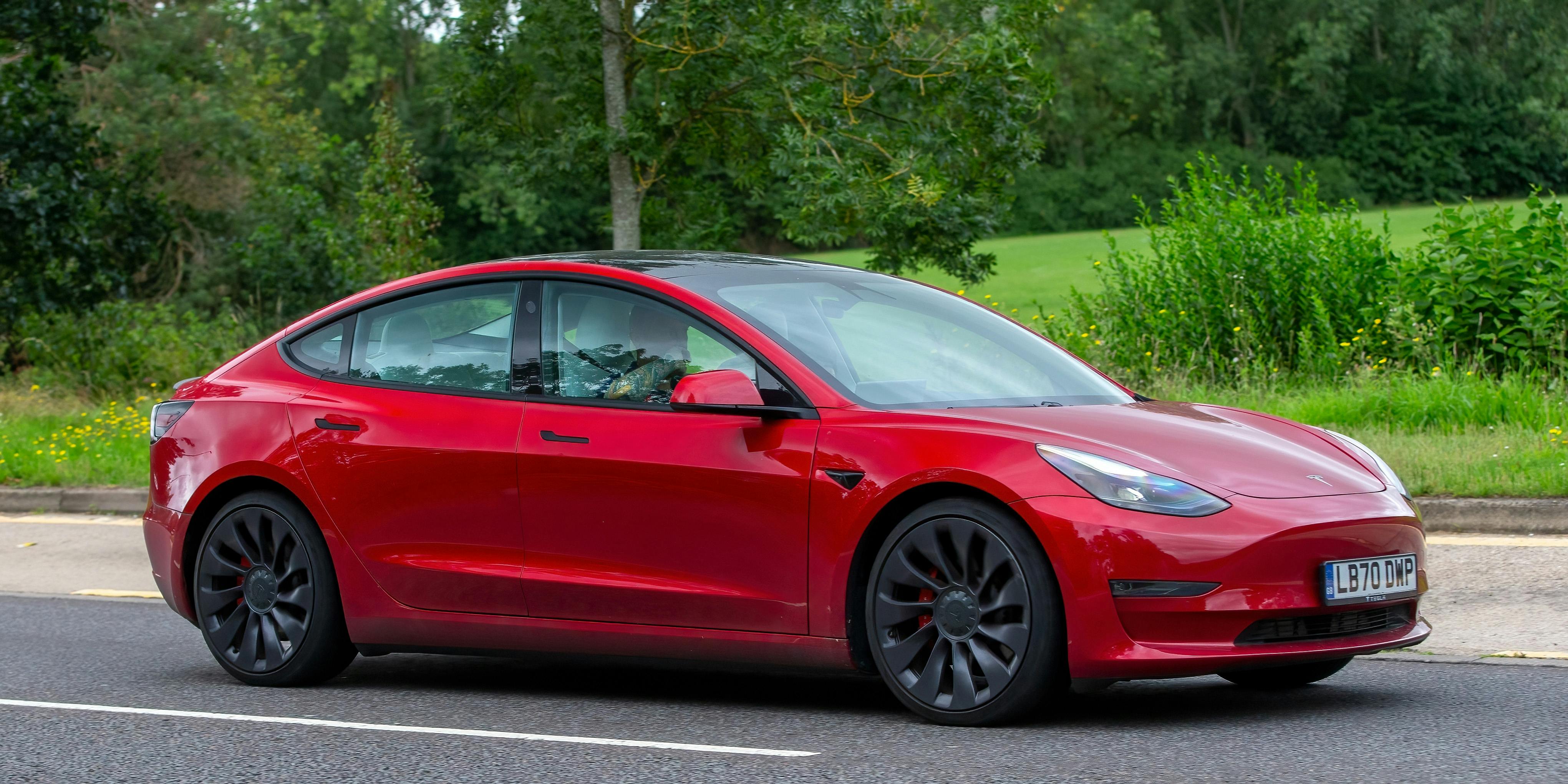 2020 red Tesla Model 3 Performance AWD electric car driving on an English country road.