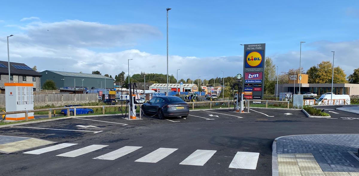 A black Tesla charges at an ultra-rapid electric car charging hub in a retail park