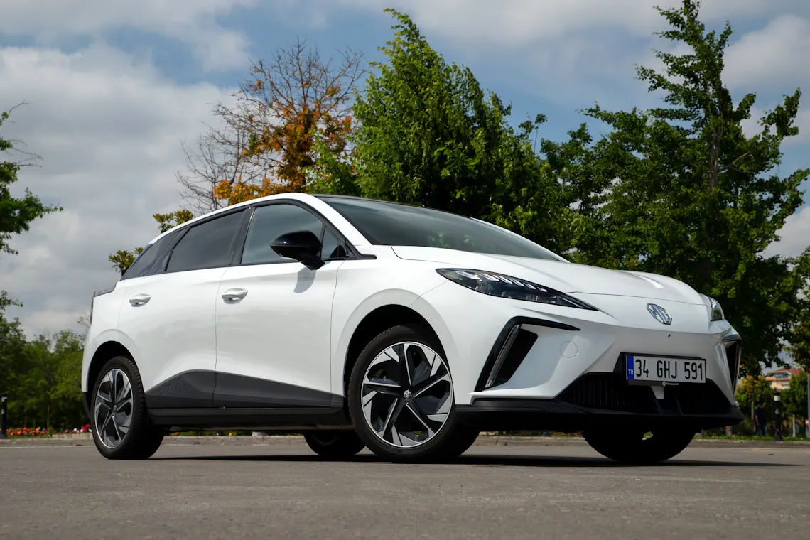 A white MG EV parked in front of trees