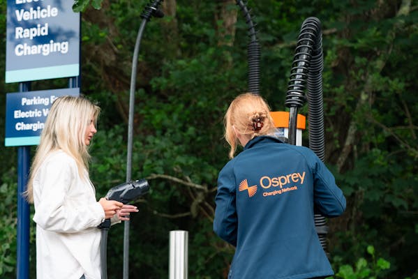 Two women unplugging the Osprey EV rapid charging cables from the charging station.