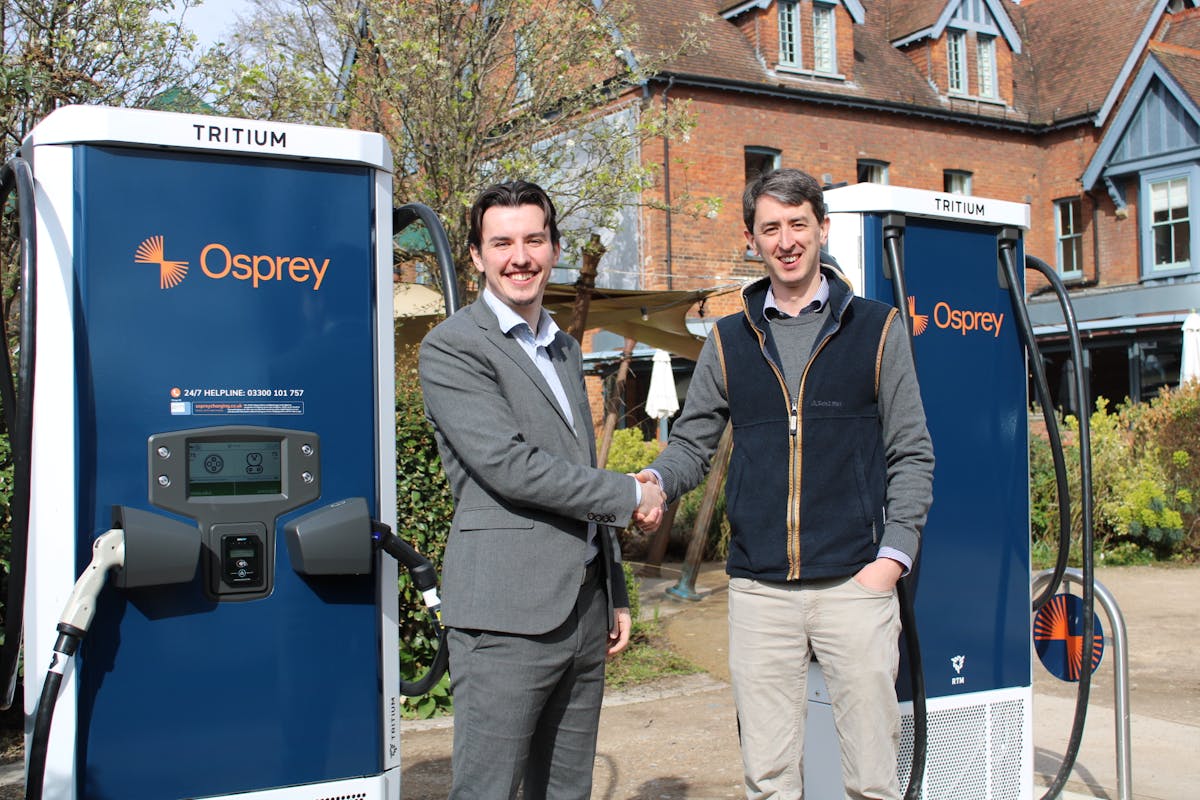 Two men shake hands in front of two Osprey rapid charging points