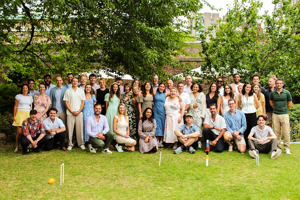 A large group of people smile for a photo in front of a croquet set