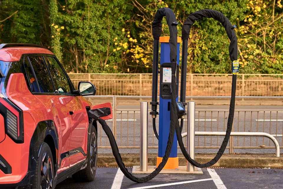 A red electric car plugged in to an Osprey rapid charger