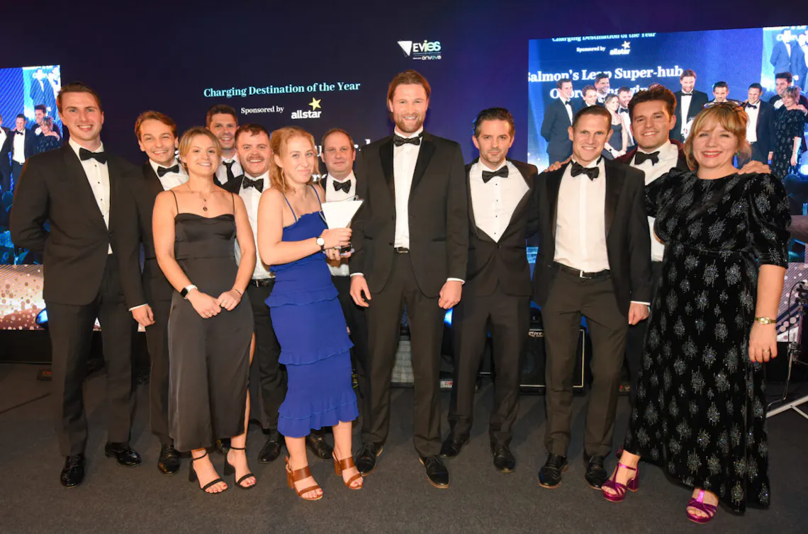 A group of people dressed in Black Tie stand together on a stage. 