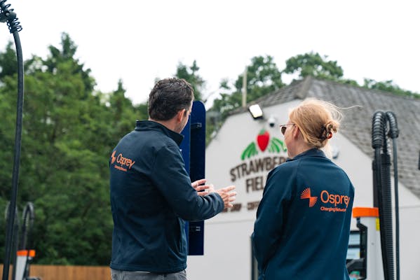 Osprey workers talking to each other at their rapid EV charging spaces.