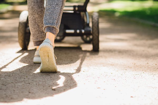 A woman pushes a pram down a path